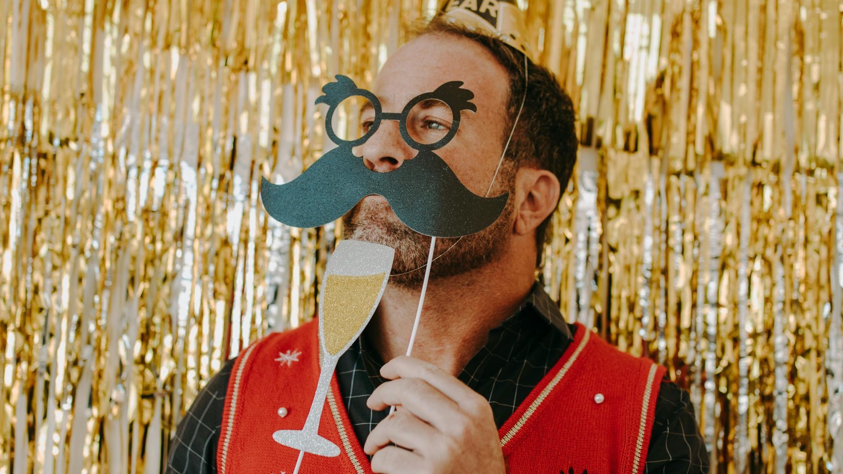 man-in-festive-attire-holding-paper-props-at-a-celebration-with-gold-decor-IlApWaSJMhRiO2b8KPyOtg